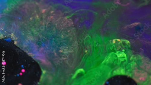 Abstract background. Paint mix bubbles. Stain art. Colorful blue pink glitter black oil ink round blot spreading in green swirls liquid in hypnotic creative design.