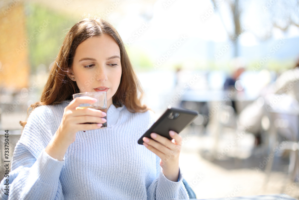 Woman drinking soda in a bar terrace checking phone Woman drinking soda in a bar terrace checking phone