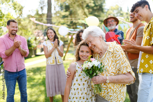 Slika na platnu Beautiful senior birthday woman receiving flowers from granddaughter