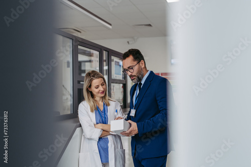 Pharmaceutical sales representative talking with doctor in medical building. Ambitious male sales representative presenting new medication on tablet.