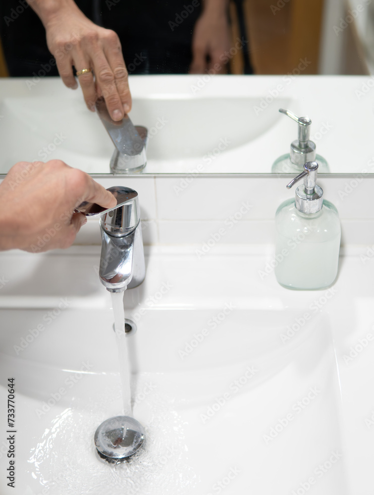 hand operating the sink water faucet. Water Restrictions and Water Resources Consumption. hand operating the sink water faucet. Water Restrictions and Water Resources Consumption.