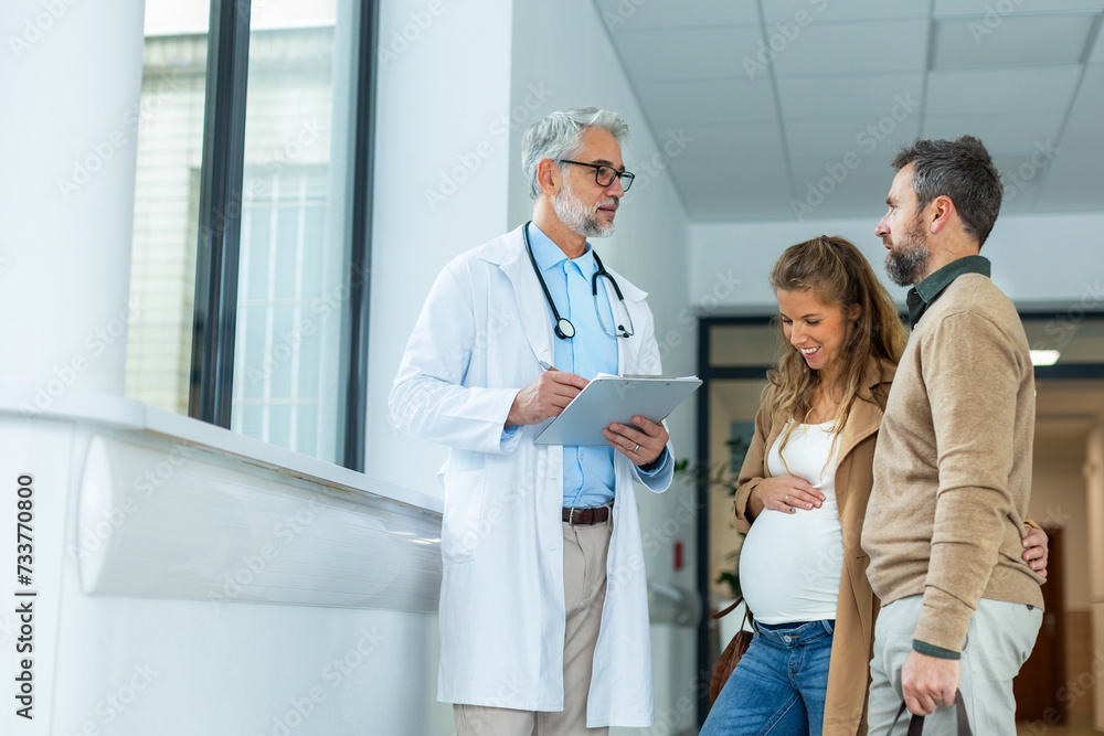 Pregnant woman and husband talking to obstetrician in hospital. Admitting woman in labor to maternity ward, planned cesarean section delivery.