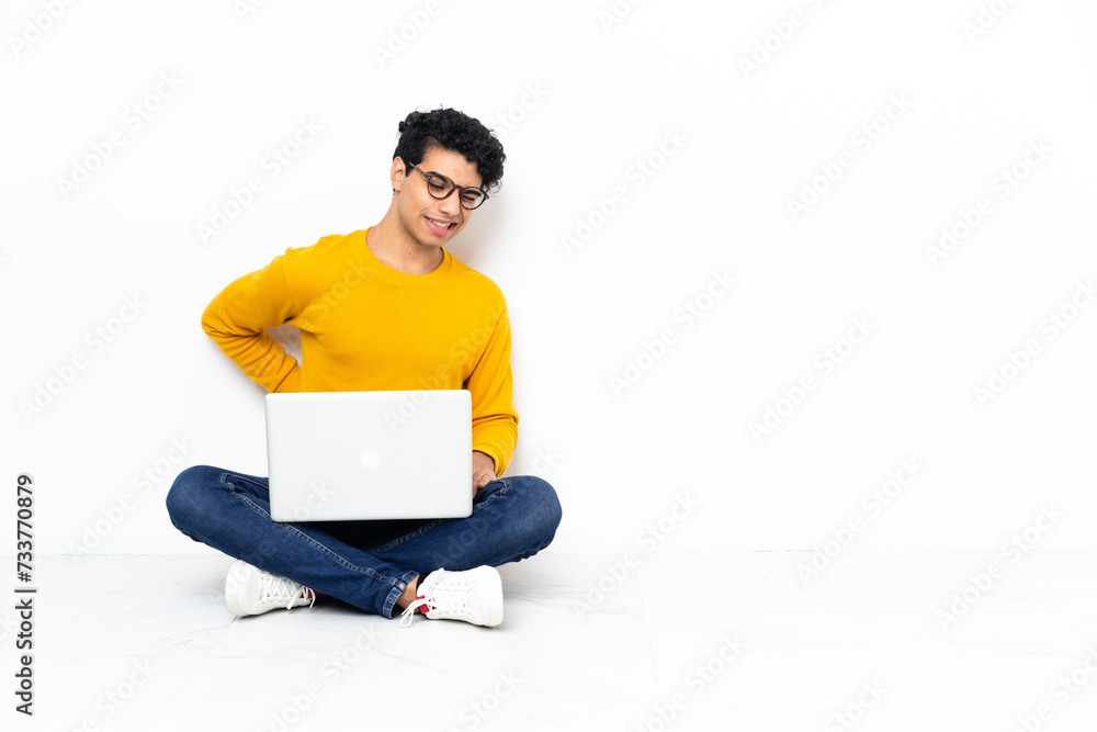 Venezuelan man sitting on the floor with laptop suffering from backache for having made an effort Venezuelan man sitting on the floor with laptop suffering from backache for having made an effort