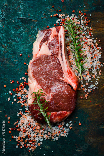 Raw steak. Beef steak with seasonings on a wooden board, close-up.