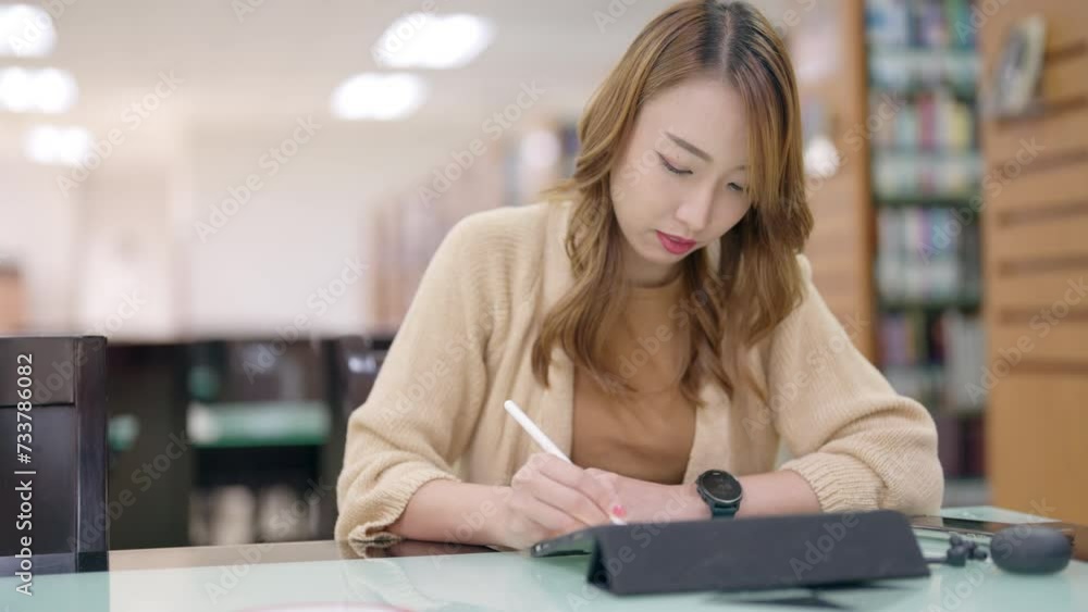 A woman studying in a library on her laptop, surrounded by books, showcasing a blend of education and technology with a smile A woman studying in a library on her laptop, surrounded by books, showcasing a blend of education and technology with a smile