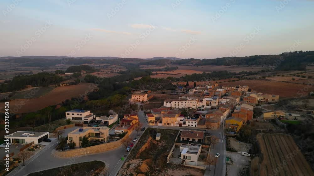 Countryside of Catalonia, perspective from above. Small villages surrounded by agriculture, mostly vine culture. Torrelavit Village. Beautiful orange sunrise colours. Drone slowly descending Countryside of Catalonia, perspective from above. Small villages surrounded by agriculture, mostly vine culture. Torrelavit Village. Beautiful orange sunrise colours. Drone slowly descending