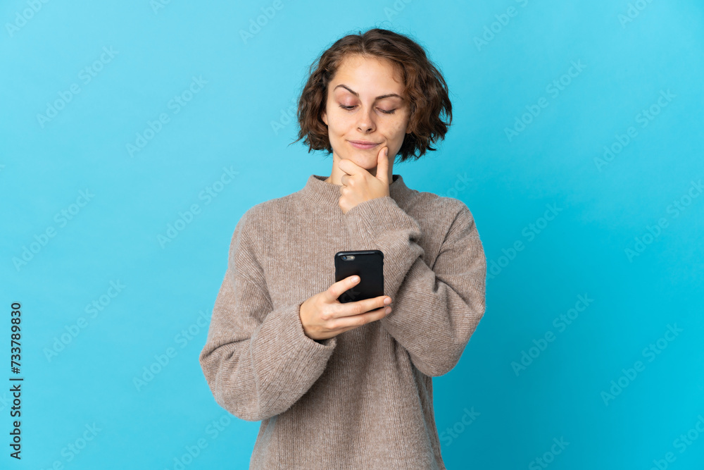 Young English woman isolated on blue background thinking and sending a message Young English woman isolated on blue background thinking and sending a message