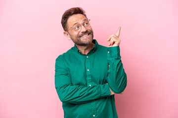 Middle age caucasian man isolated on pink background pointing up a great idea
