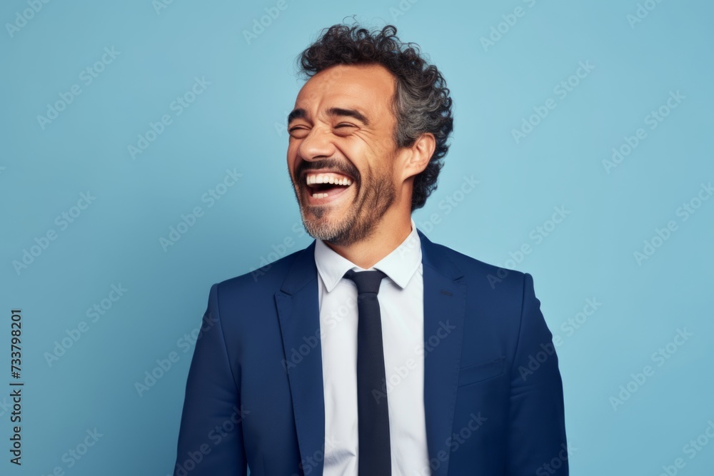 Handsome middle-aged man laughing and looking at camera against blue background Handsome middle-aged man laughing and looking at camera against blue background