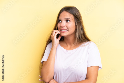 Young caucasian woman isolated on yellow background is a little bit nervous