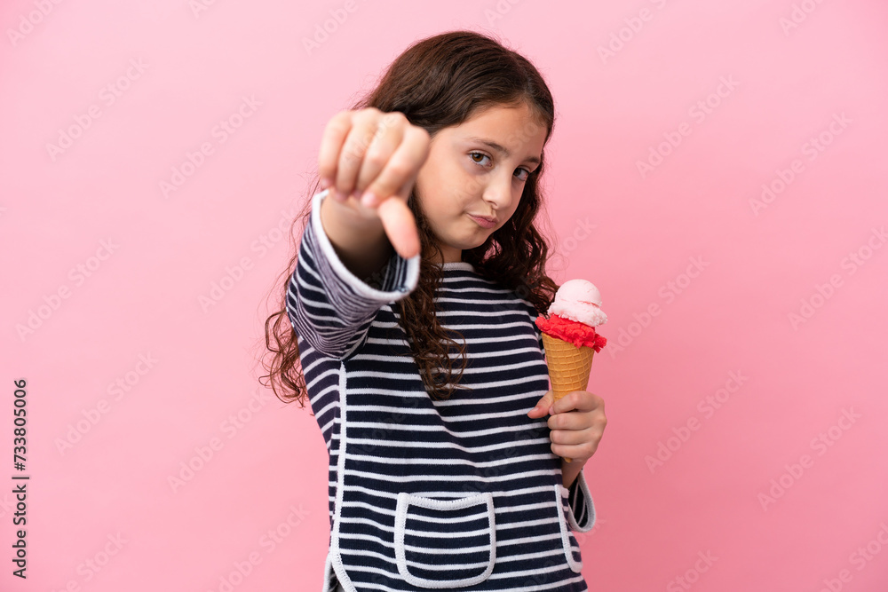 Little caucasian girl holding an ice cream isolated on pink background showing thumb down with negative expression Little caucasian girl holding an ice cream isolated on pink background showing thumb down with negative expression