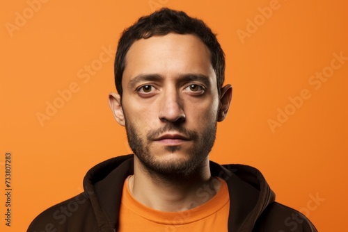 Portrait of a young man looking at camera isolated on orange background