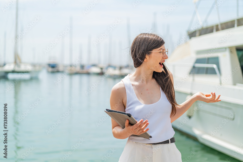 Φωτογραφία Young pretty Ukrainian woman holding a tablet at outdoors with surprise facial e