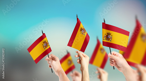 A group of people are holding small flags of Spain in their hands.