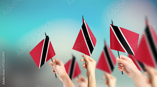 Fototapeta Naklejka Na Ścianę i Meble -  A group of people are holding small flags of Trinidad and Tobago in their hands.
