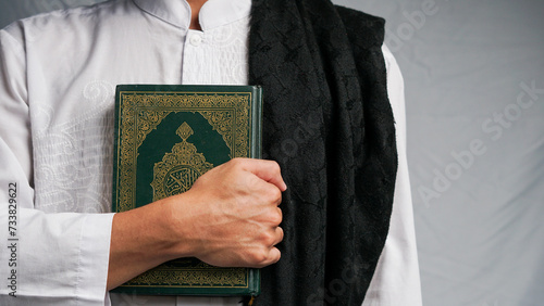 A man is embracing the Koran with a prayer mat in his hand