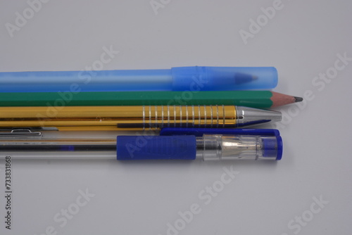 Office, stationery, green pencil, golden, blue, blue ballpoint pens placed on white background.