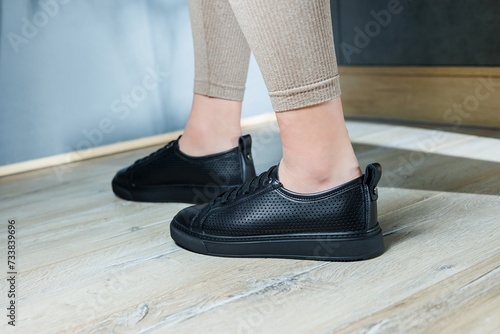 Collection of women's shoes. Black leather sneakers on women's feet. Female feet in comfortable casual sandals