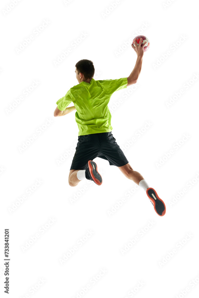 Fototapeta premium Full-length image of young handball athlete in motion during game, throwing ball against white studio background. Motivation to win. Concept of professional sport, tournament, competition