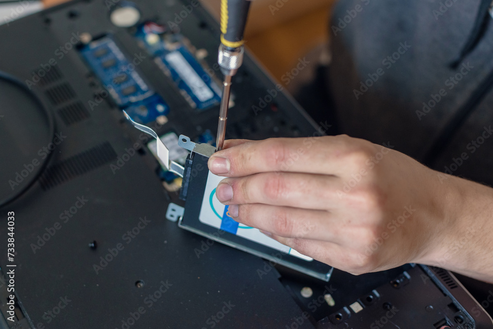 Closeup photo of male technician with screwdriver replacing hdd disk of laptop, Hard disk rescue: Expert conducts precise repairs on a laptop, salvaging crucial data