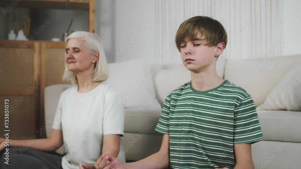 Grandma and grandson meditating and concentrating on their feelings, clearing thoughts out. Senior woman and her grandson calming their minds. Family staying in house and having fun during lockdown Grandma and grandson meditating and concentrating on their feelings, clearing thoughts out. Senior woman and her grandson calming their minds. Family staying in house and having fun during lockdown