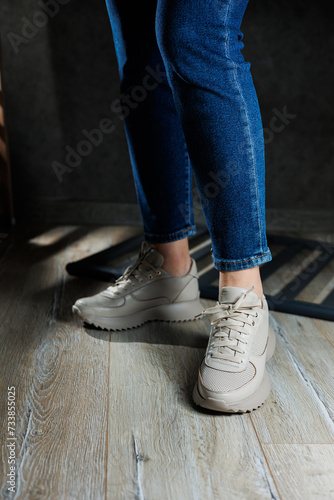 Beige women s sneakers. Collection of women s leather shoes. Female legs in leather beige casual sneakers. Stylish women s sneakers.