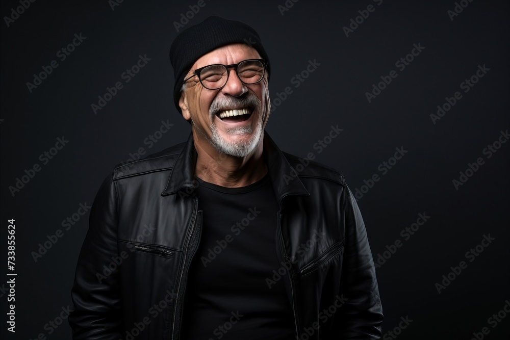 Portrait of a happy senior man laughing while wearing a black leather jacket and hat.