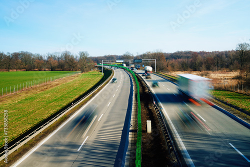 Long exposure shot of busy highway with silhouettes of driving cars on road. Traffic on motorway with motion blurred cars