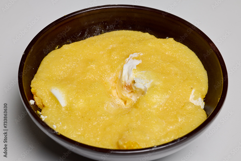 (Mamaliga) with cheese, eggs, and cream in a plate. (Mamaliga) with cheese, eggs, and cream in a plate.