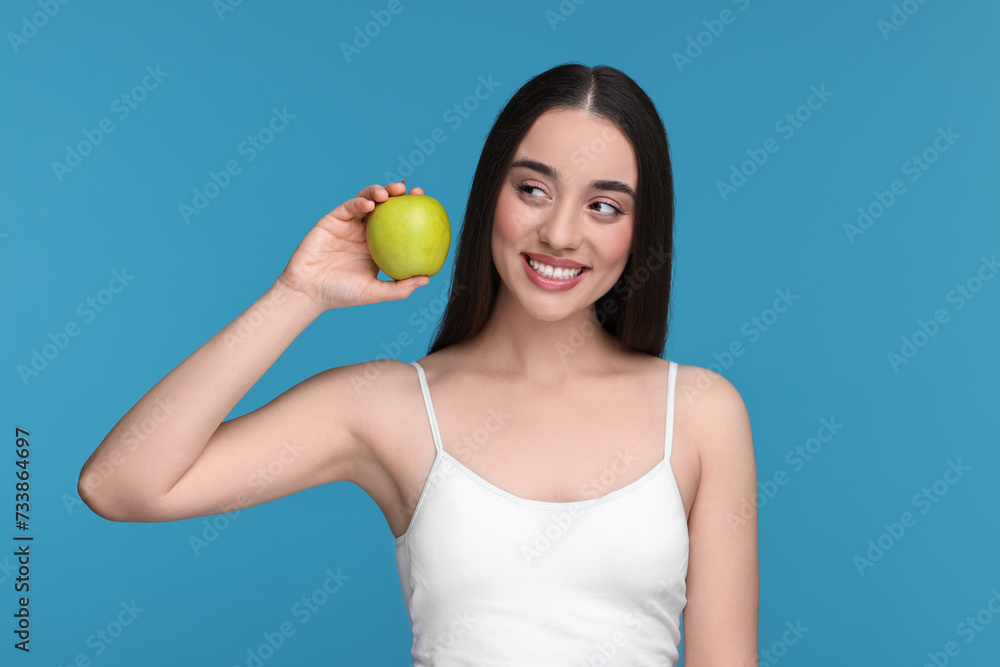 Beautiful young woman with apple on light blue background Beautiful young woman with apple on light blue background