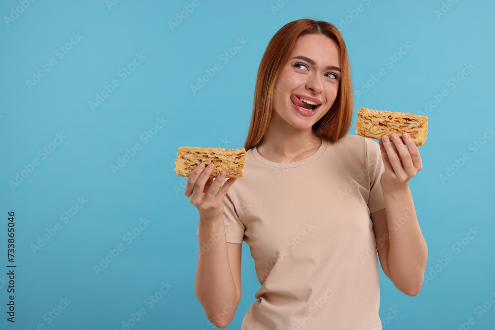 Young woman with pieces of tasty cake on light blue background, space for text Young woman with pieces of tasty cake on light blue background, space for text