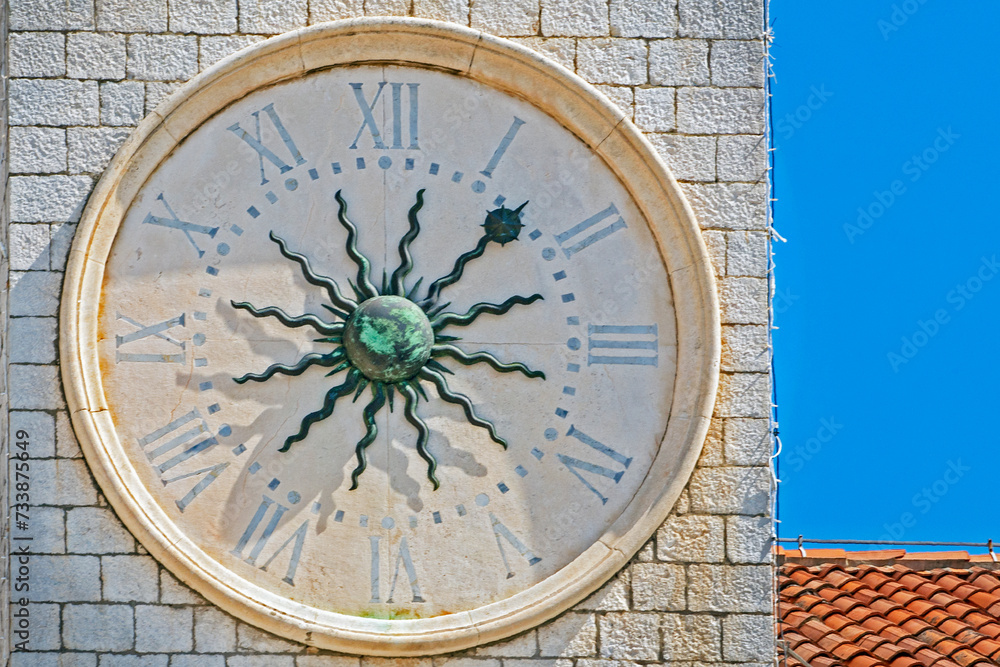 antique clock with a copper sculpted sun in the middle against the sky