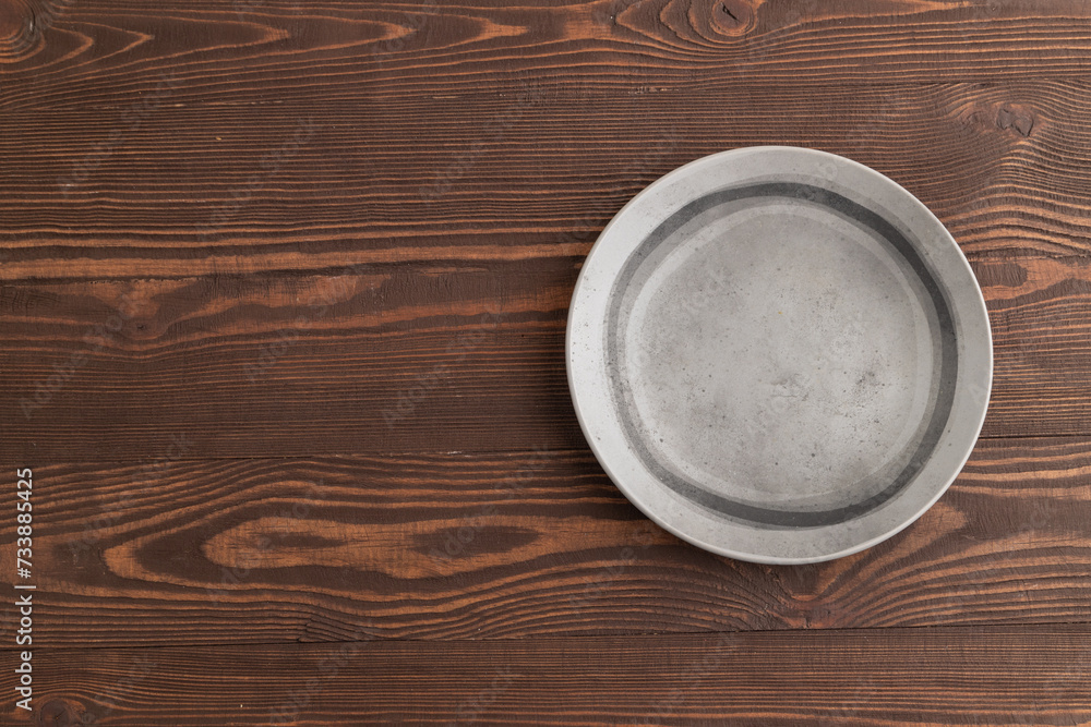 Empty gray ceramic plate on brown wooden background. Top view, copy space Empty gray ceramic plate on brown wooden background. Top view, copy space