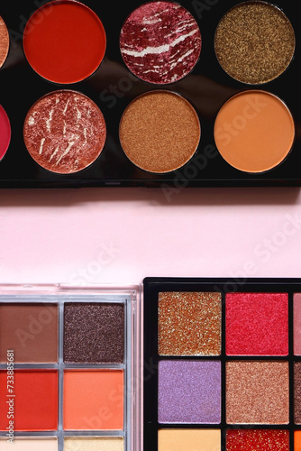 Various colorful eyeshadow palettes on bright pink background. Flat lay.