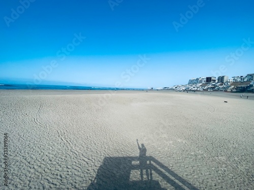 Playa peruana  solitaria con mar de fondo, sombra de persona.