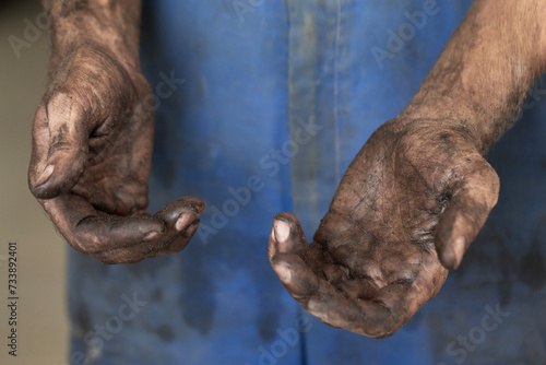 Dirty hands of a young man in blue overalls, auto mechanic, close-up. © Юлия Черкасова