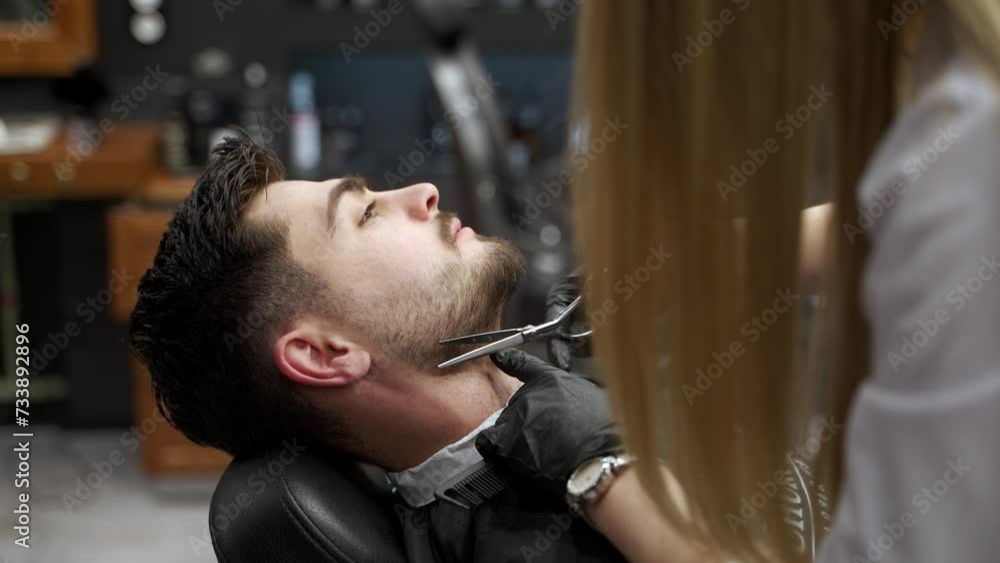 Professional barber provides grooming services, sharpens mans beard with razor in modern salon. Male client enjoys precise facial hair trim, styles look in barbershop. Shaving process detailed in HD. Professional barber provides grooming services, sharpens mans beard with razor in modern salon. Male client enjoys precise facial hair trim, styles look in barbershop. Shaving process detailed in HD.