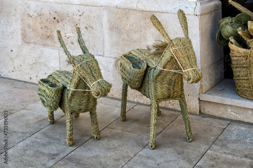 two small esparto grass donkeys on a street at the entrance of a store photo