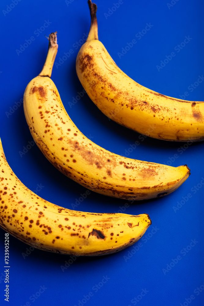 Rotten bananas on a blue background from above. Bananas that are beginning to spoil. Yellow rotten bananas. Food waste.