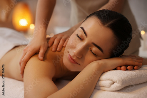 Woman receiving back massage on couch in spa salon