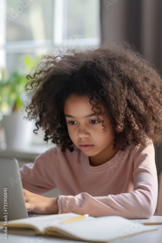 African American little girl with curly hair sitting at the table  writing and doing homework