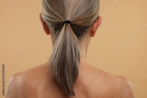 Mature woman with healthy skin on beige background, back view