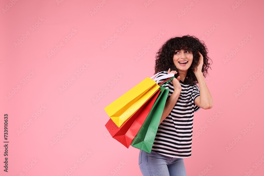 Happy young woman with shopping bags on pink background. Space for text Happy young woman with shopping bags on pink background. Space for text