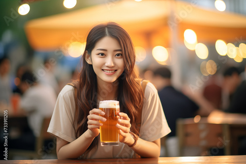 Young pretty Chinese woman at outdoors drinking beer