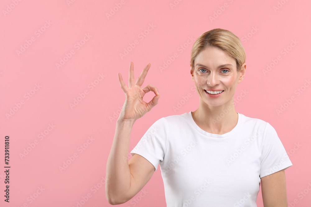 Woman with clean teeth smiling and showing OK gesture on pink background, space for text Woman with clean teeth smiling and showing OK gesture on pink background, space for text