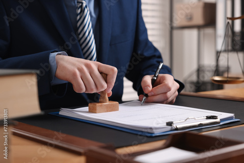 Billede på lærred Notary with pen stamping document at table in office, closeup