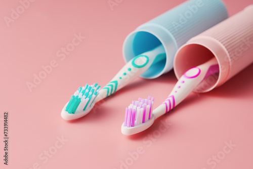 Two toothbrushes in a case on a pink background from a low angle view.