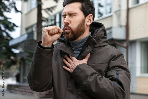 Sick man coughing on city street. Cold symptoms