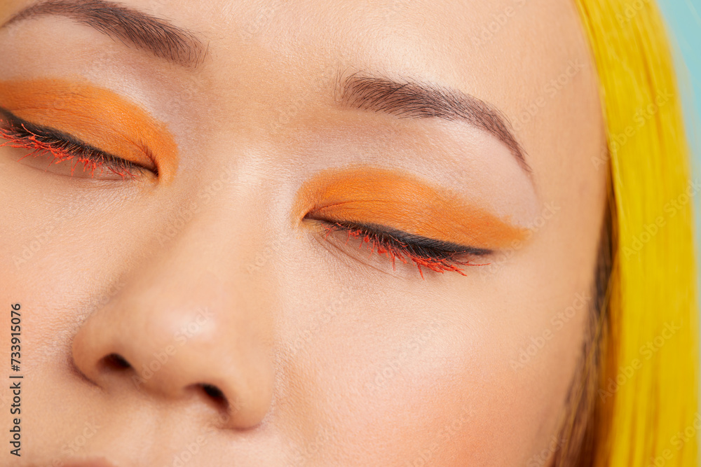 Young woman with orange make up, eyes closed