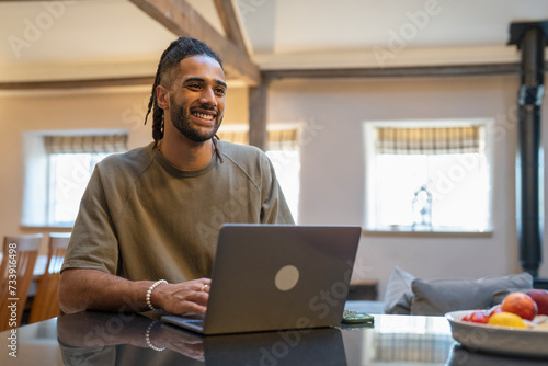 Man with dreads working on laptop at home photo